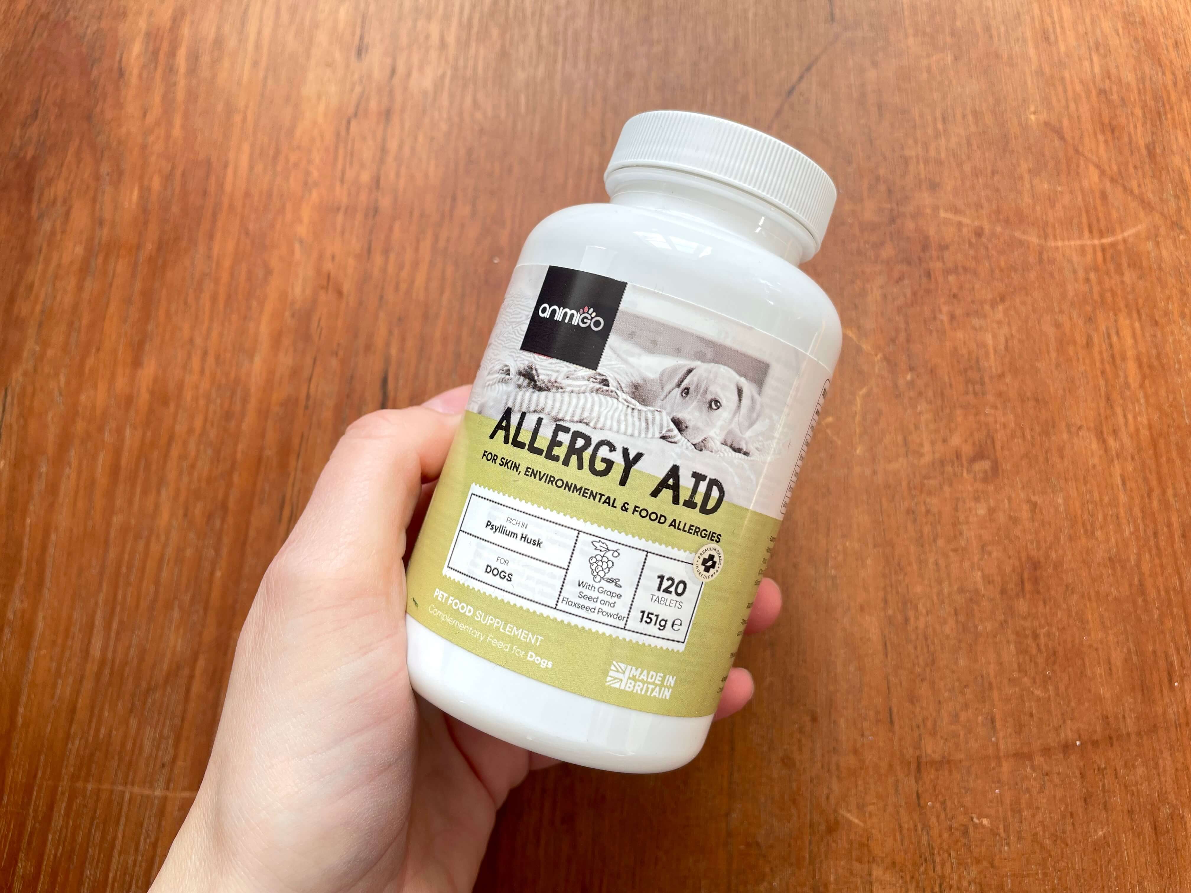Bøtte med Allergy Aid holdes af person