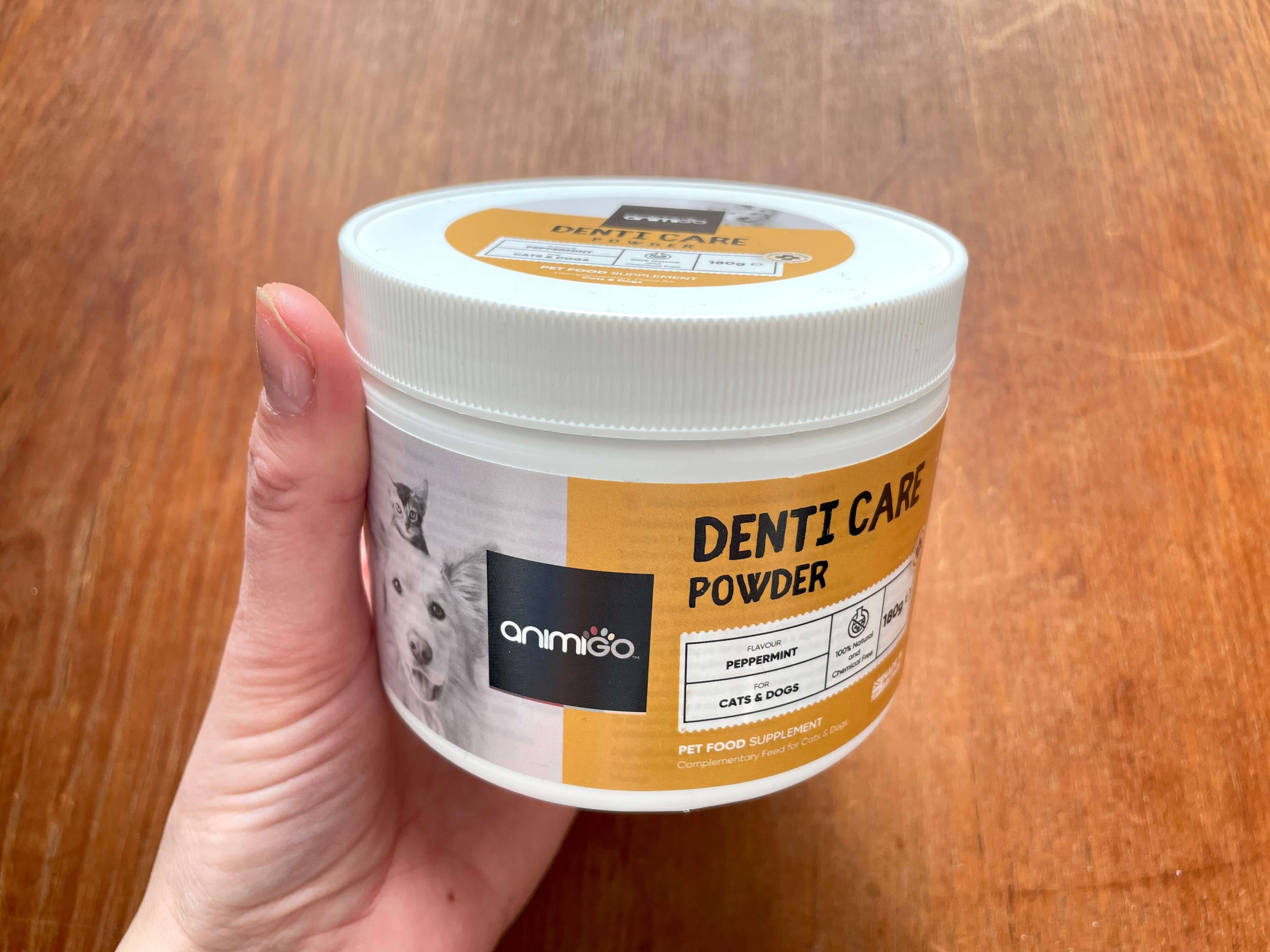 Hånd der holder Denti Care pulver fra Animigo