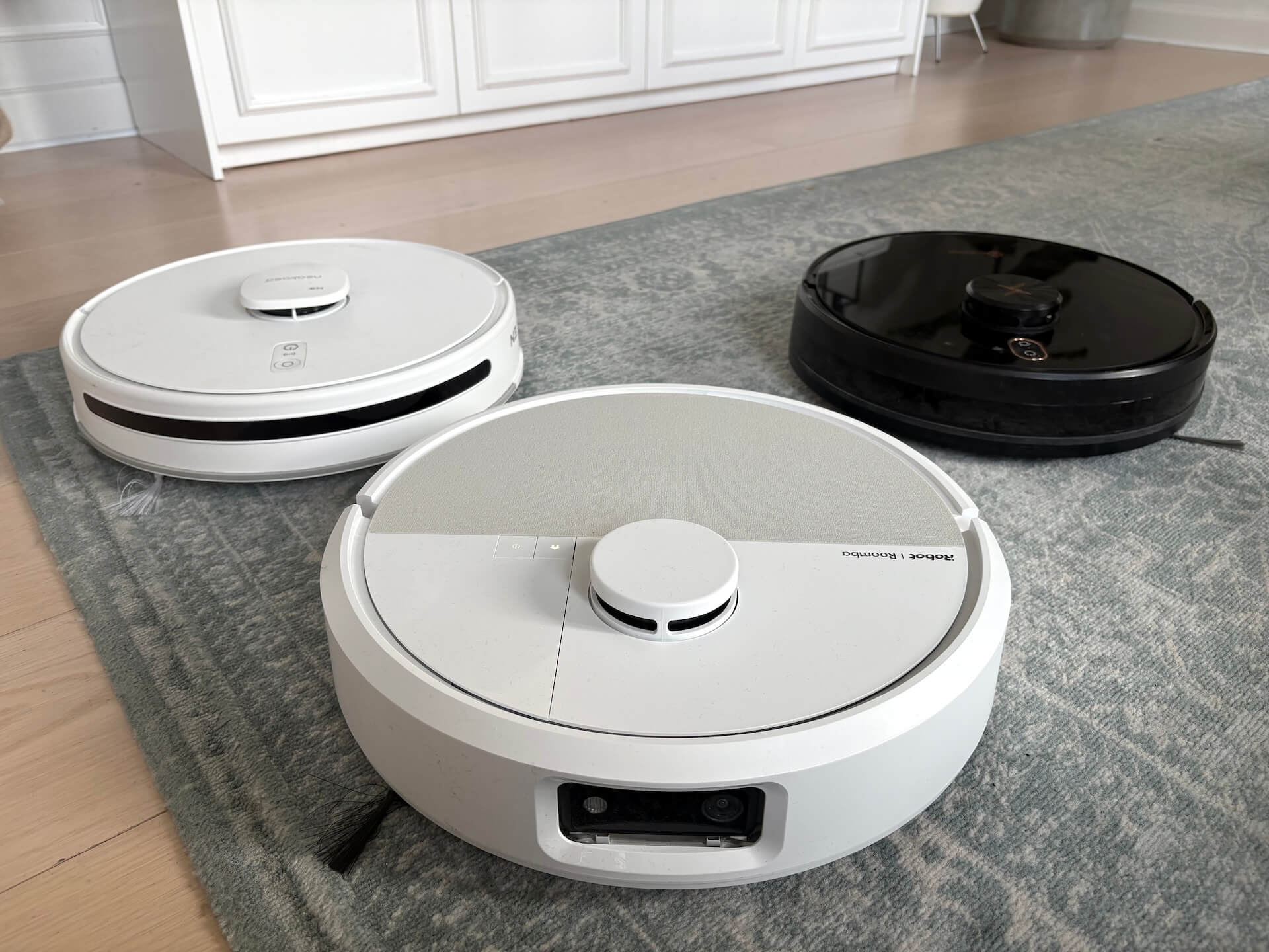 iRobot Roomba Plus 505 foran Neatsvor X650 Pro og Neakasa N3 på et gulvtæppe