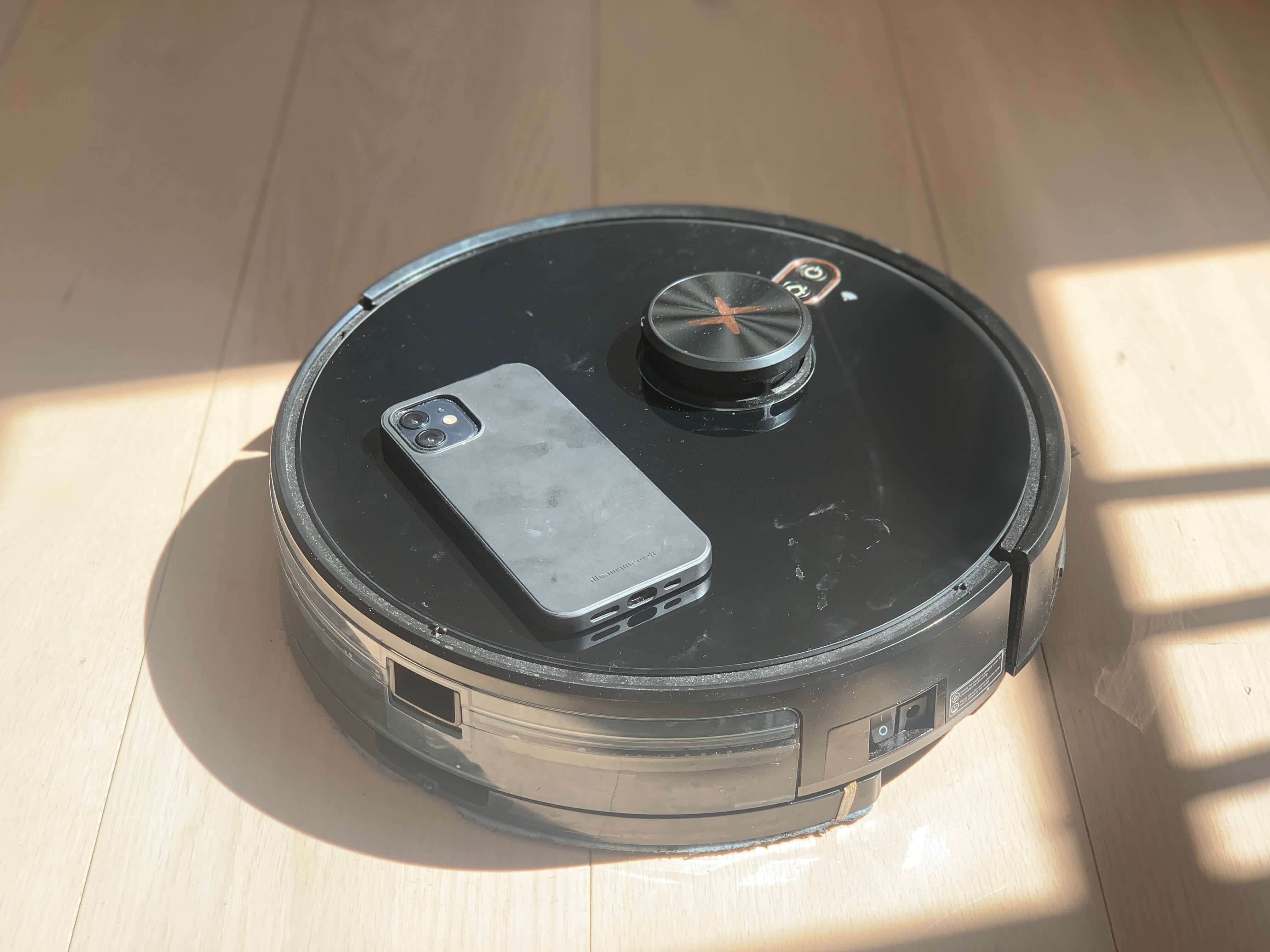 Robotstøvsuger med smartphone APP med smartphone liggende oven på
